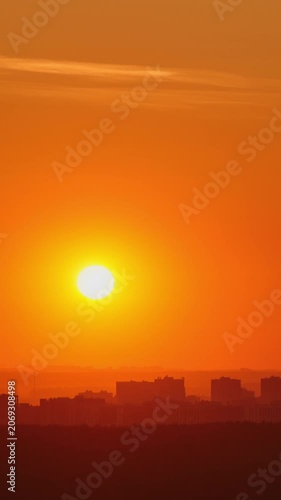 Orange sun setting over city skyline. Silhouette of urban buildings under bright evening sky. Beautiful sunset background for travel, ecology and nature concept in city environment.