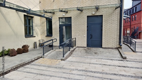 Fotografie An inclined ramp made of concrete tiles with metal handrails was made to allow people with disabilities to enter the building