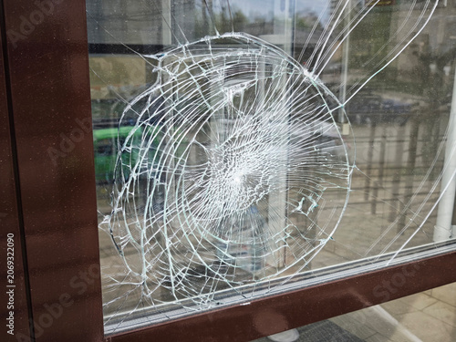 Obraz na plátně Broken glass in a window showing impact point and cracks during daylight