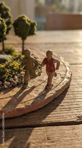 Handcrafted Miniature Diorama Featuring Two Small Toy Figures On A Playful Creative Journey Outdoors