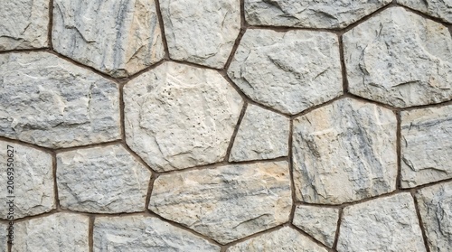 Close up view of a decorative light grey stone wall with natural texture and irregular shapes for architectural exterior design