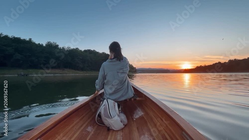 Woman paddling canoe at sunset on peaceful lake
