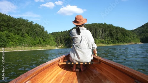 Slow motion of woman canoeing across peaceful lake