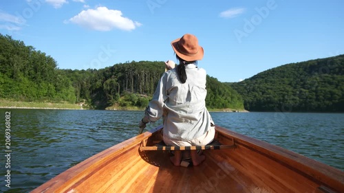 Rear view of man paddling canoe on calm lake in daylight