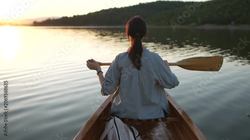 Rear view of woman canoeing during golden sunset