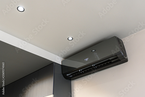Tableau sur toile sleek dark-gray wall-mounted air conditioner displays 30° on its digital panel