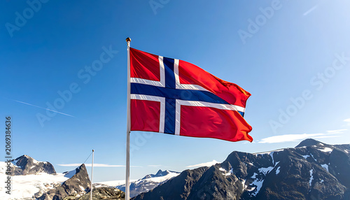 Waving Norwegian flag on a flagpole against a clear blue sky, with snow-capped mountains in the background, symbolizing national pride and travel