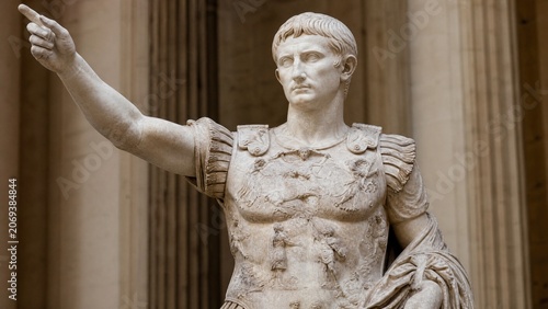 Classical marble statue of a Roman emperor in a colonnade setting.