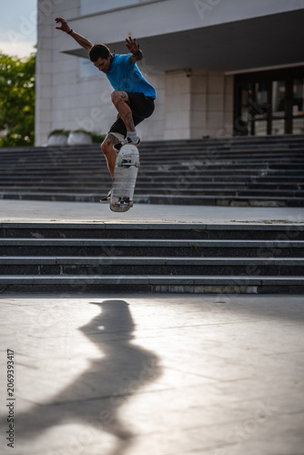 Obraz na plátne Skateboarder performing kickflip in front of national theatre