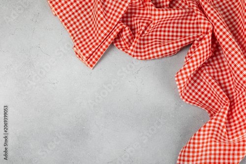 Picnic tablecloth on a textured wooden background. Checkered red picnic cloth crumpled. Kitchen towel, tablecloth. Checkered napkin. Food decor element. Space for text. Copy space. Design