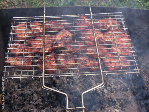 Fotografie Grilled meat pieces on barbecue grill with smoke and charcoal