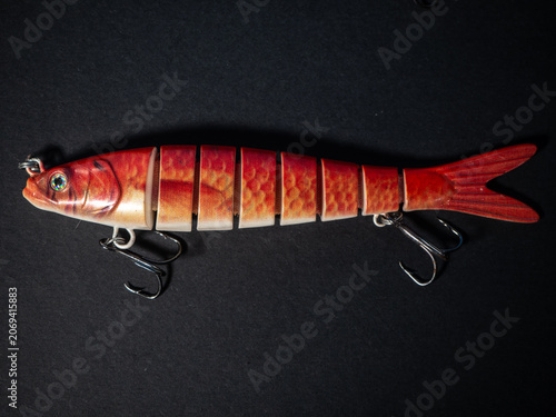 Foto Jointed orange fishing lure bait on black background