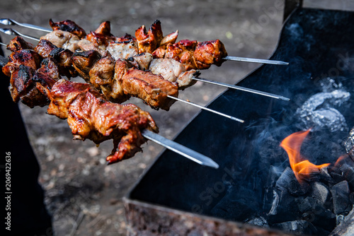 Photography Appetizing kebabs on skewers over charcoal in a barbecue grill in nature
