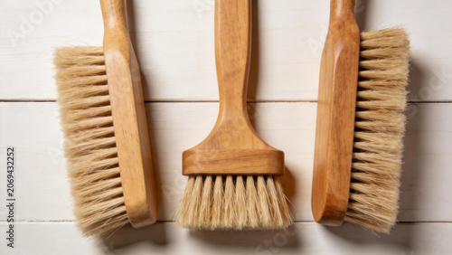 Three wooden cleaning brushes on white wood background