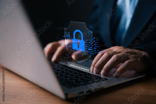 Businessman typing on laptop with digital shield, padlock, and password hologram. Represents cybersecurity, data protection, secure login, encryption, and safe internet browsing.