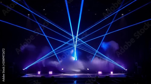 Dynamic blue laser beams intersecting on a dark stage with smoke and strobe lighting. Entertainment and live concert show concept