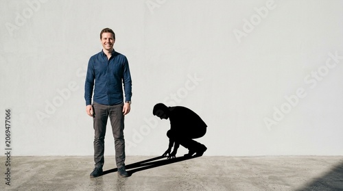 Man standing next to his shadow in a starting position, representing readiness and potential