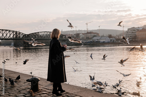 Bild auf Leinwand Young woman enjoying a cup of coffee in cozy cafe on the Vltava river embankment in Prague during winter
