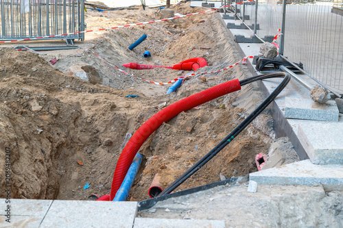 Bild auf Leinwand An open construction trench along a city street, revealing underground pipes and