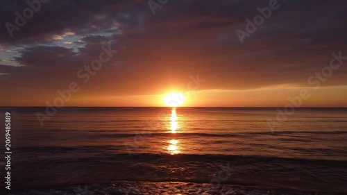 Beautiful golden sunset over the calm ocean with dark clouds
