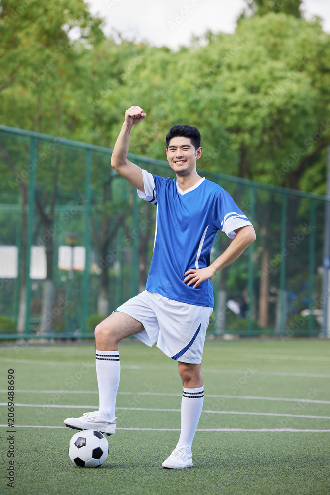 Obraz premium Confident young soccer player celebrating on outdoor football field