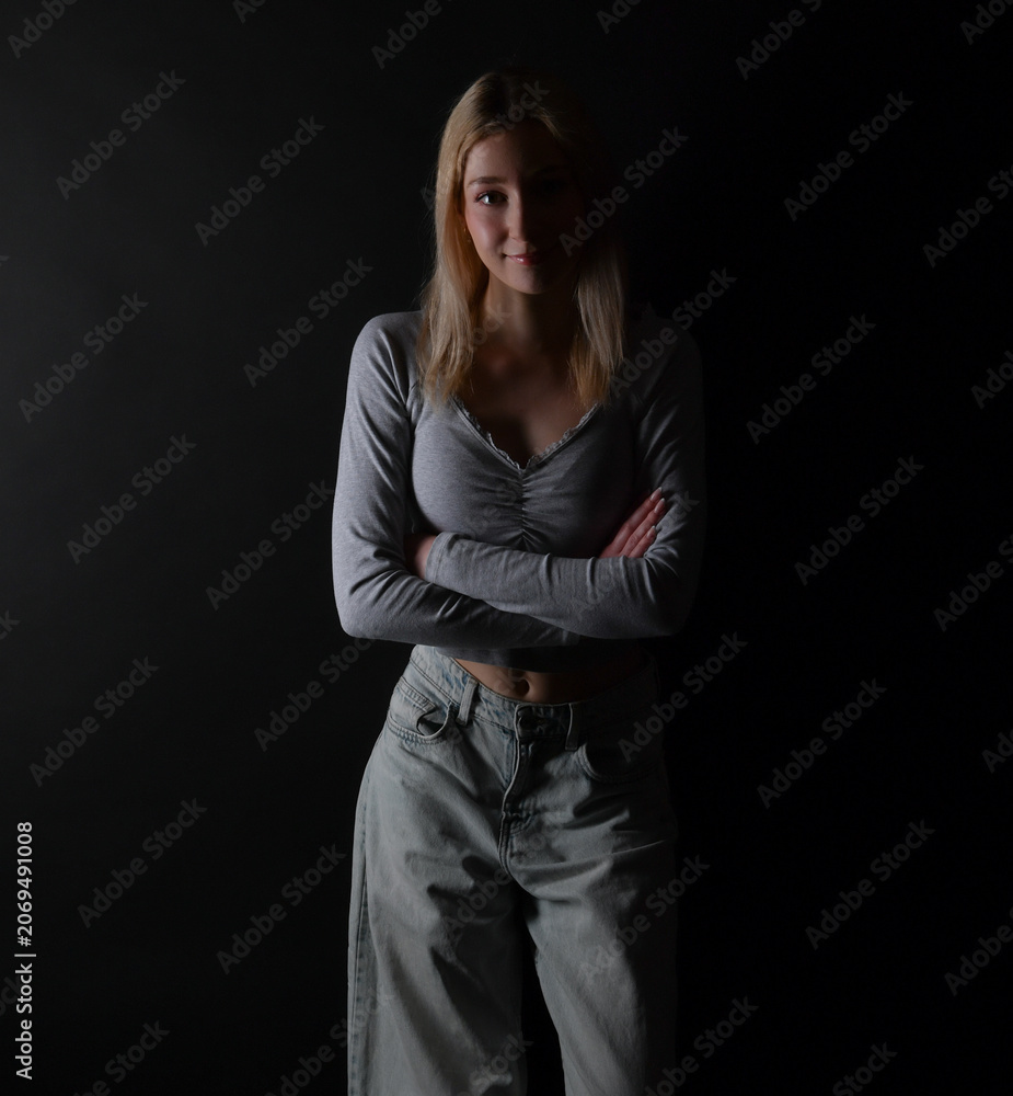 Fototapeta premium Junge Frau in dramatischer Low-Key-Beleuchtung vor dunklem Hintergrund. Ausdrucksstarkes Porträt für Emotionen, Selbstreflexion, mentale Gesundheit und Persönlichkeit.