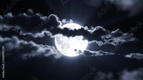 A bright full moon shines through dark dramatic clouds at night