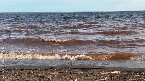 Waves crashing on shore of reservoir after storm in daylight  