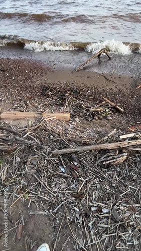 Shoreline after storm with driftwood and waves on reservoir. Mobile vertical video  