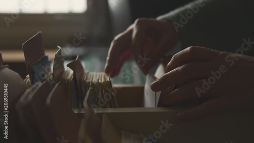 Woman searching through paper index cards in archival cabinet, retro information system and history concept, 4K
