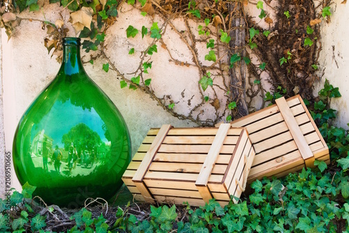 Decorative Green Glass Bottle with Wooden Crates and Ivy Against Stone Wall