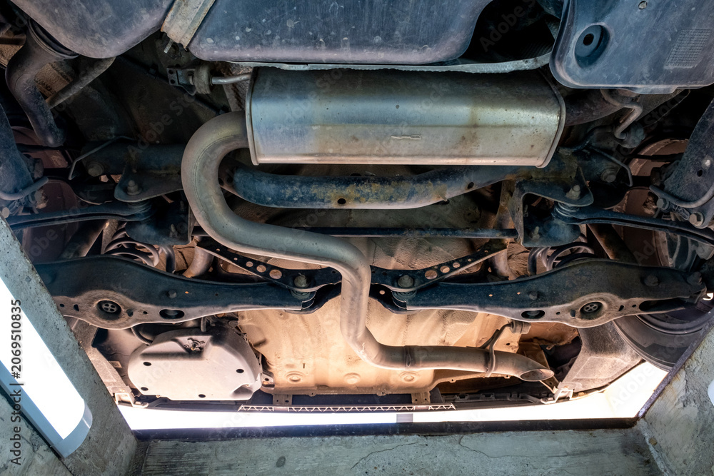 Fototapeta premium Undercarriage View of Car Exhaust System, Suspension and Chassis Components in Auto Repair Inspection Pit