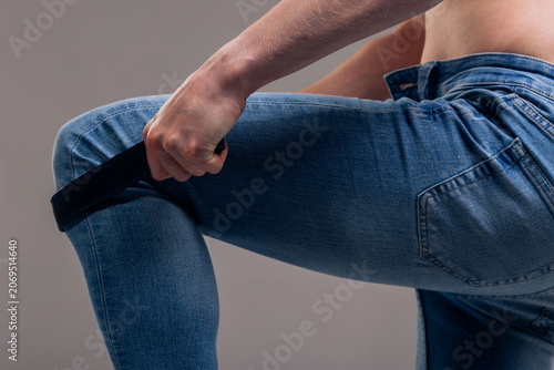 Cuadro en lienzo A muscular man in blue classic jeans with a bare torso is holding a belt