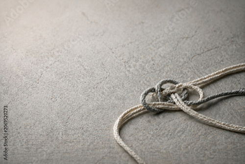 White and gray rope knot on concrete surface. Space for text.