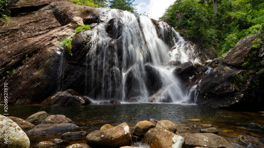 Fototapeta premium Waterfall cascading over rocks in lush green forest