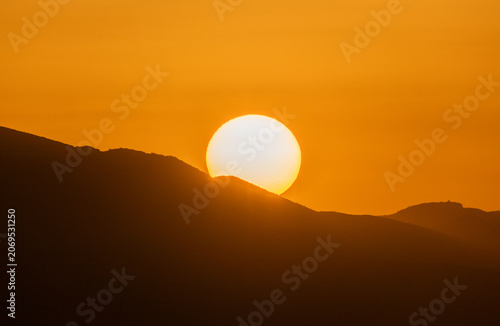 Extreme heatwave during El Nino phenomenon with sun setting over mountain range