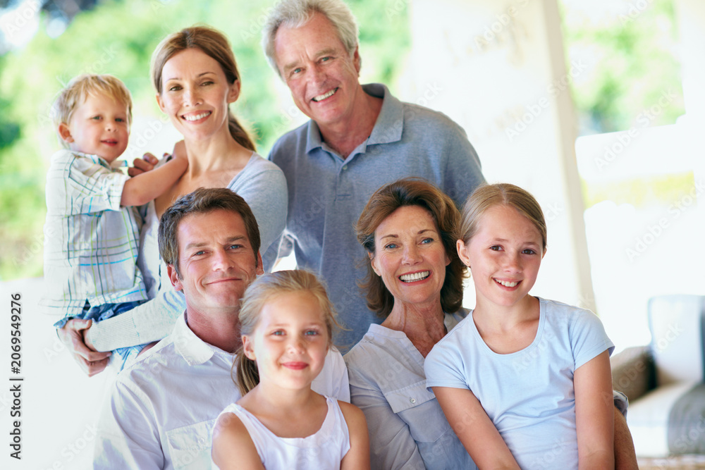 Obraz premium Portrait, big family and happy on patio for bonding, love and care with generations outdoor. Grandparents, parents and children with people on home porch, smile or relax together for trust and memory