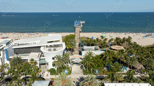 Aerial view of the iconic Pompano Beach Pier stretching into the Atlantic Ocean, surrounded by palm-lined beaches and South Florida's vibrant waterfront.