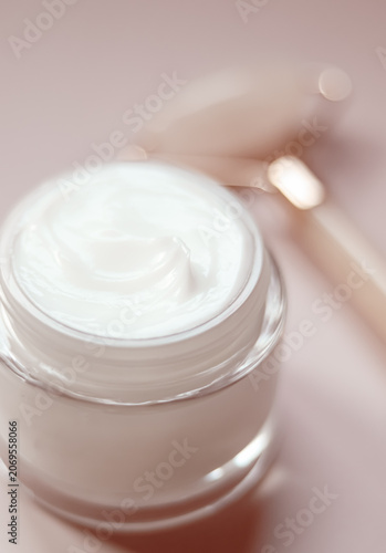 Face cream in a glass jar with rose quartz roller for daily skincare routine and luxurious beauty treatment
