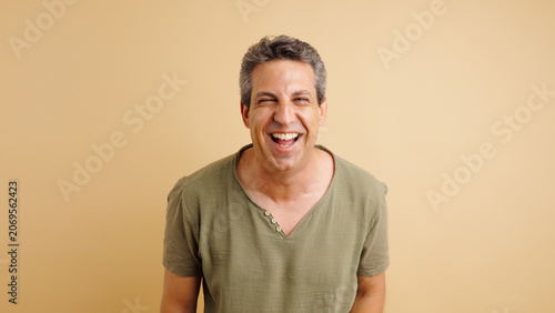 Middle aged man laughing enthusiastically, showing genuine happiness and positive feelings on a solid background with copy space