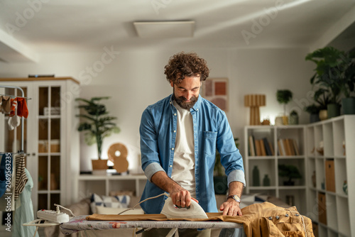 Tableau sur toile Man ironing clothes managing household chores at home