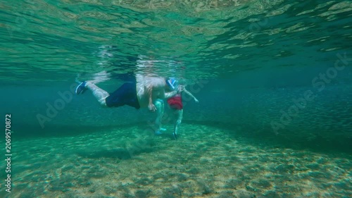 Team of snorkelers encounters a colossal bait ball just a few yards from the beach. They family move gently to stay within the tight cluster of glimmering Silverside Atherina school