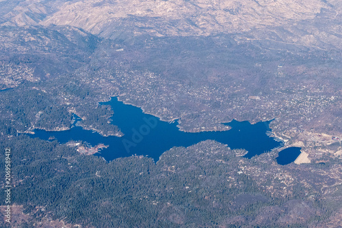 Aerial view of Lake Arrowhead in the San Bernardino Mountains, California, USA. The lake's deep blue waters are surrounded by a dense pine forest, characteristic of the region