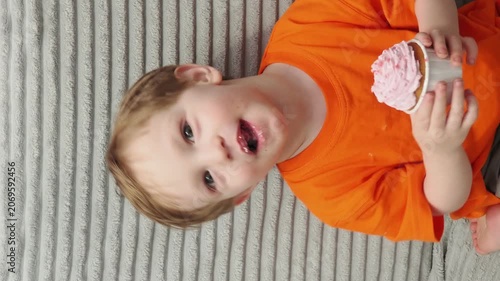 Child Eating, cupcake for dessert, sweet treat or sugar snack . Boy Bite, tasting vanilla cake with pink cream on top, hungry and enjoy delicious food. Happy childhood: a child enjoys a sweet treat
