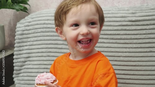 Child Eating, cupcake for dessert, sweet treat or sugar snack . Boy Bite, tasting vanilla cake with pink cream on top, hungry and enjoy delicious food. Happy childhood: a child enjoys a sweet treat