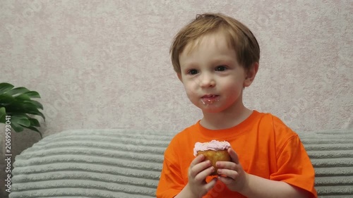 Child Eating, cupcake for dessert, sweet treat or sugar snack . Boy Bite, tasting vanilla cake with pink cream on top, hungry and enjoy delicious food. Happy childhood: a child enjoys a sweet treat