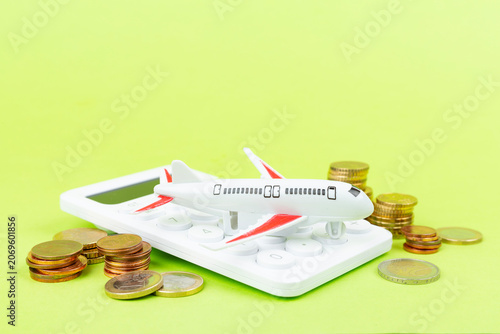 Model of airplane with coins and calculator on color background