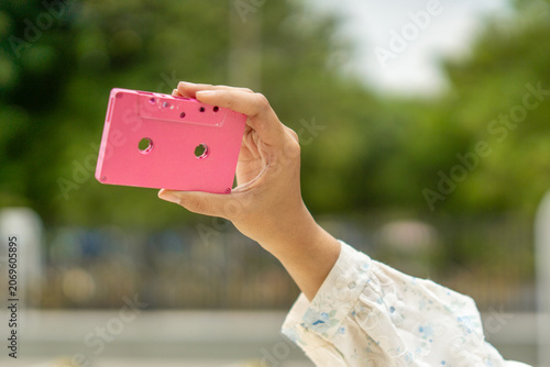 Hand holding a pink cassette. A tool for recording and storing music in the past.