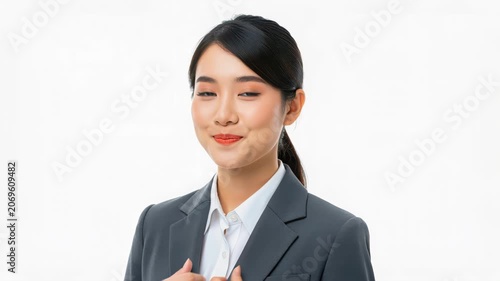 Professionalism Personified: A poised young Asian businesswoman in a sharp grey suit and white blouse exudes confidence and competence, her subtle smile hinting at quiet determination and success.