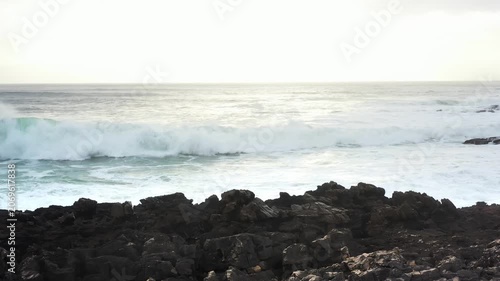 Nature's power unfolds as waves surge and crash against sharp rocks. A tranquil twilight embraces the coast, reflecting the beauty of ocean and earth merging.